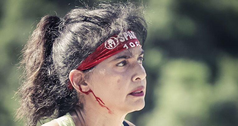 Saili Gosula competing in a Spartan Race, wearing a red headband and yellow tank top, focused and determined during an outdoor endurance challenge.